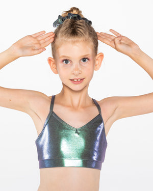 A young gymnast wearing a red Mystique crop top with a shiny, metallic fabric. She has her hands on her hips and is smiling at the camera.