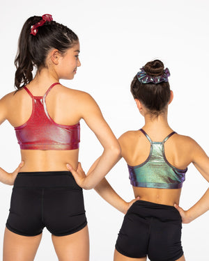 Two women wearing sports bras and black shorts on a white background