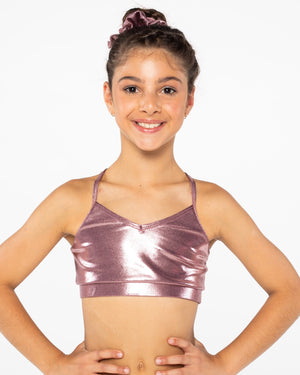 A young gymnast wearing a red Mystique crop top with a shiny, metallic fabric. She has her hands on her hips and is smiling at the camera.