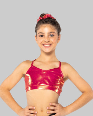 A young gymnast wearing a red Mystique crop top with a shiny, metallic fabric. She has her hands on her hips and is smiling at the camera.